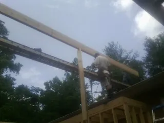 Carpenter setting a ridge beam over a new addition frame — Ice Dam Removal by Roofing Brothers in Watford City