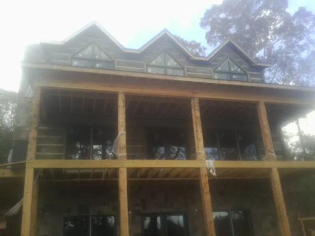 Dormers and porch framing on a large log home under construction — Roof Coating work by our crew in Watford City