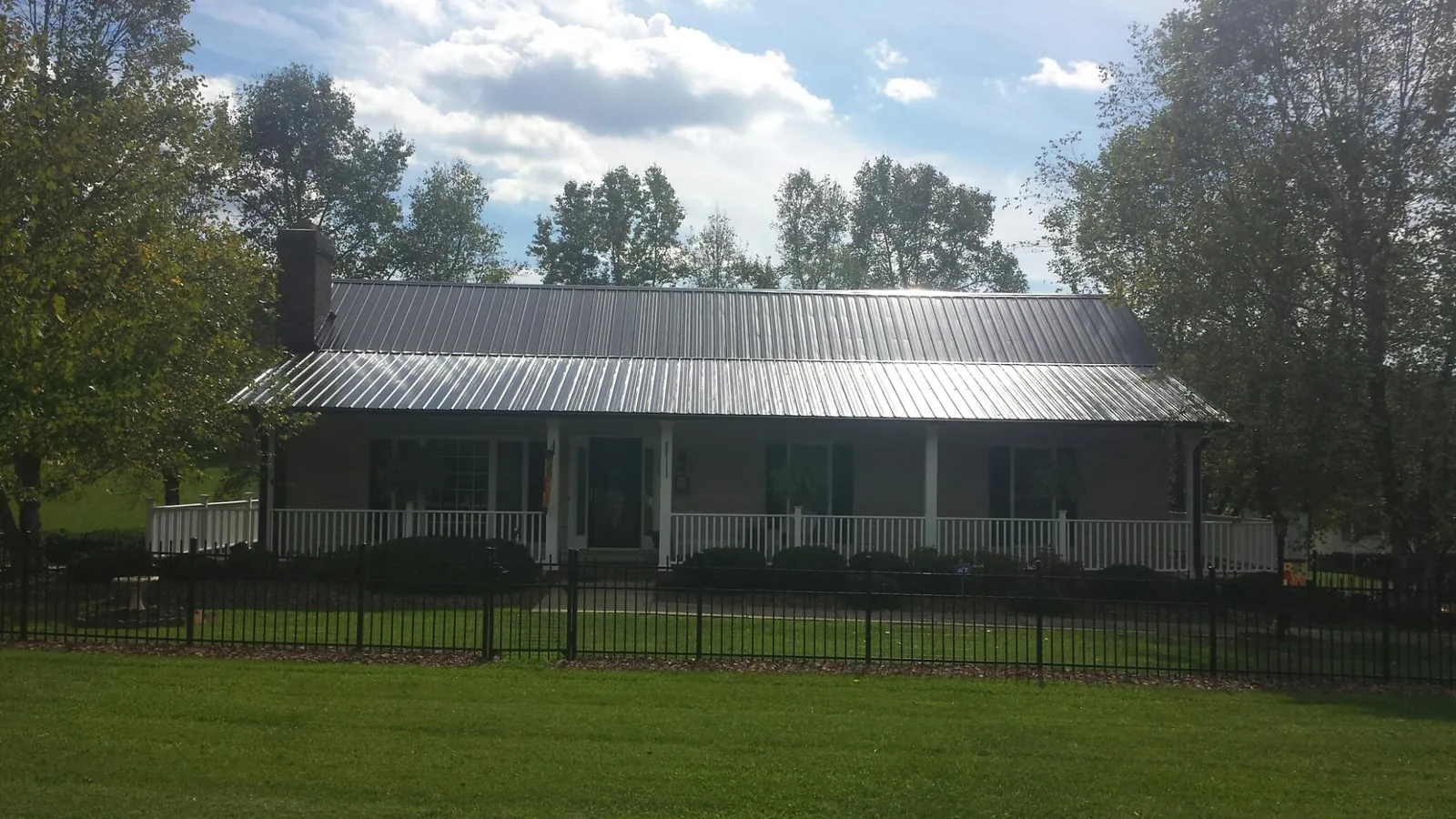 Gray metal roof on a brick ranch with a full width front porch — Gutter Guard Installation work by our crew in Watford City