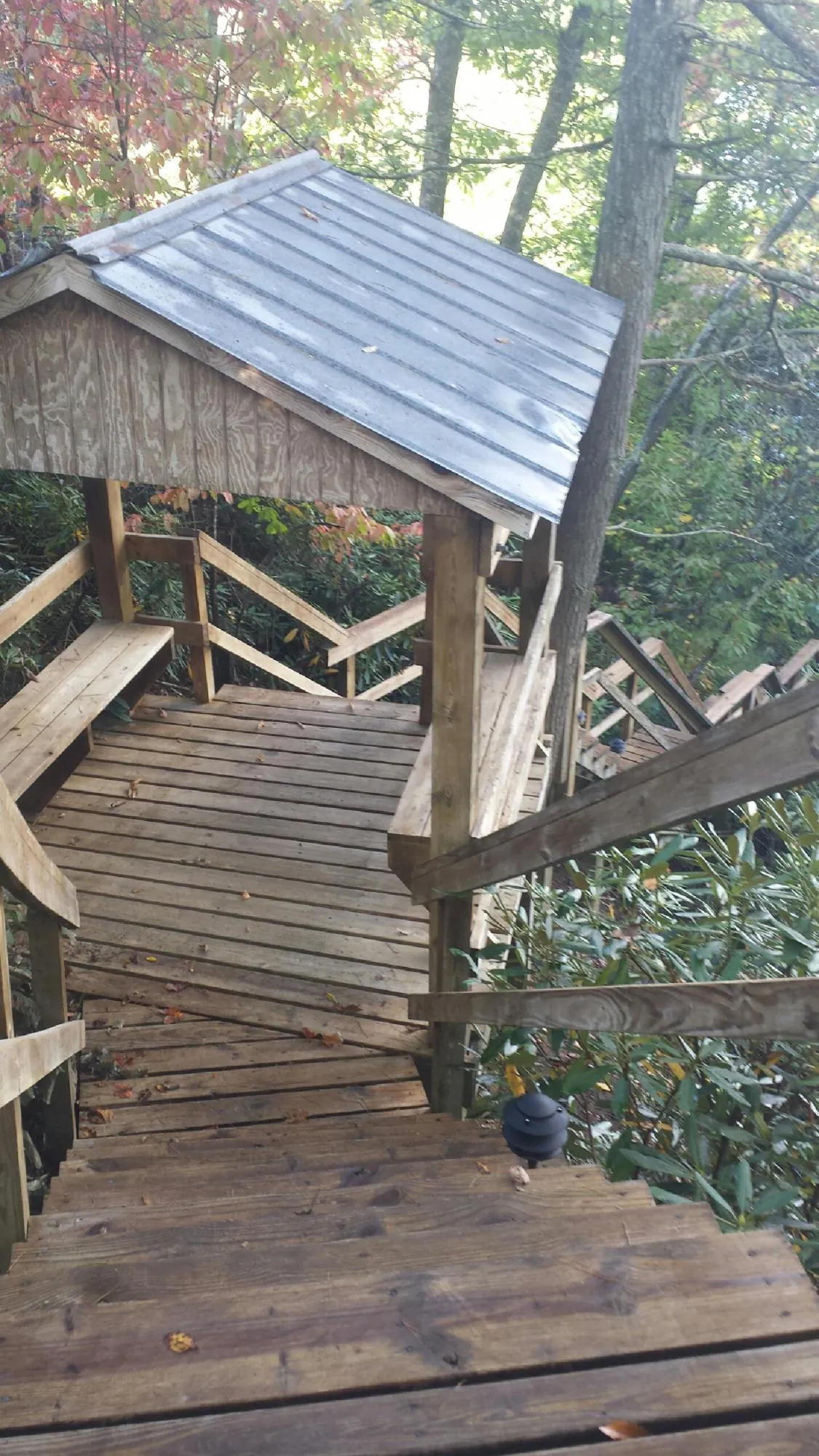 Metal roofed shelter over wooden steps on a wooded walkway — Skylight Repair & Installation work by our crew in Watford City