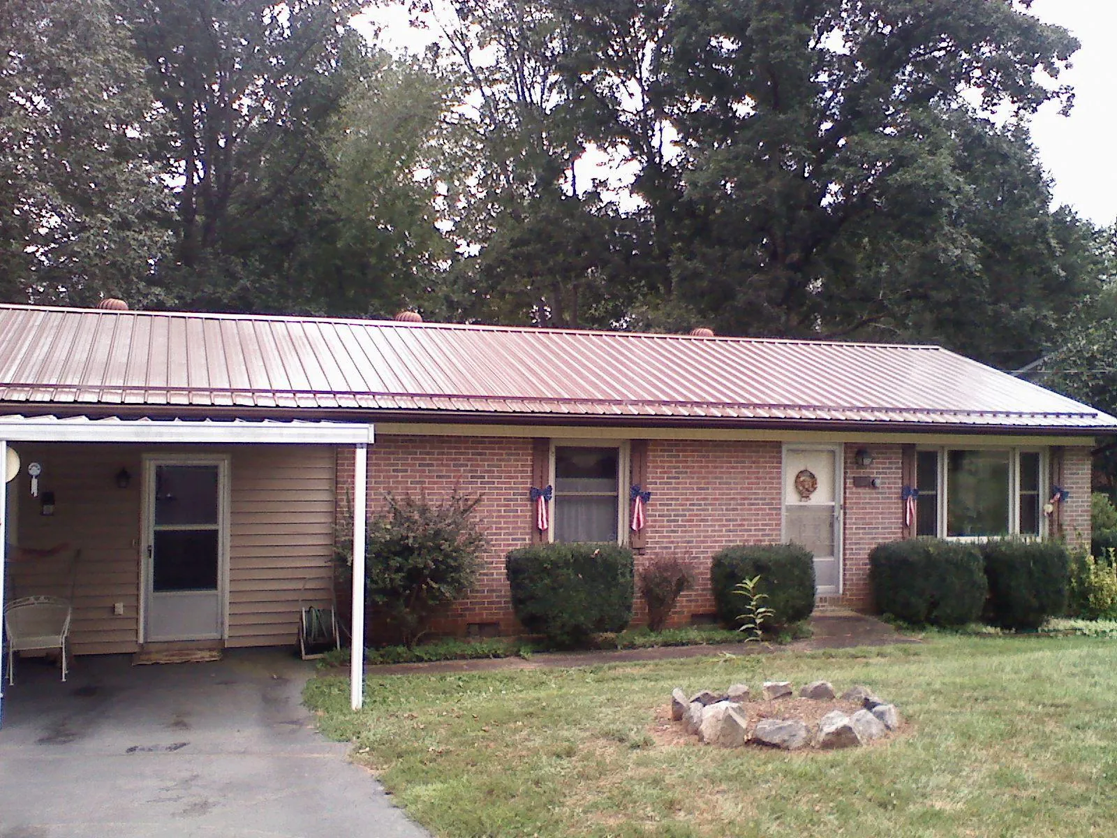 Bronze metal roof and carport on a brick ranch home — Roof Repair work by our crew in Watford City
