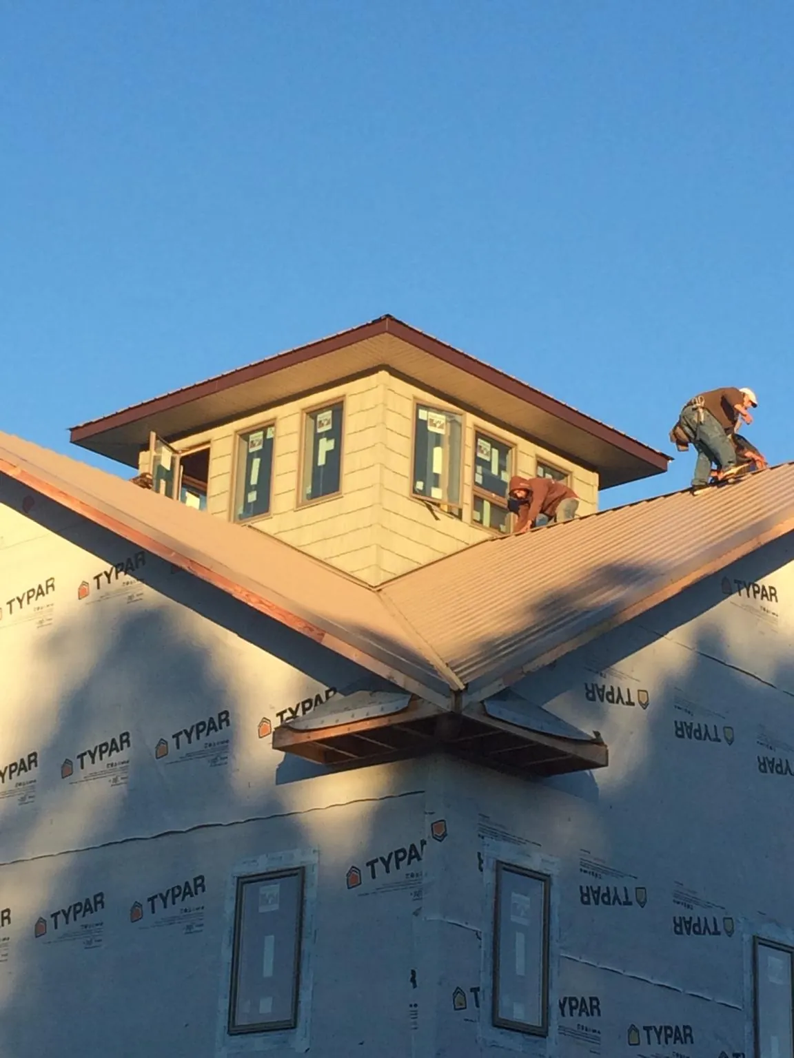 Roofers working around a rooftop cupola on a new metal roof at sunset — Roof Waterproofing in Watford City by Roofing Brothers